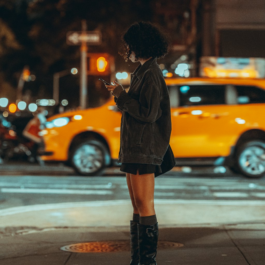 Photo of a woman on a city street at dusk checking directions on her phone