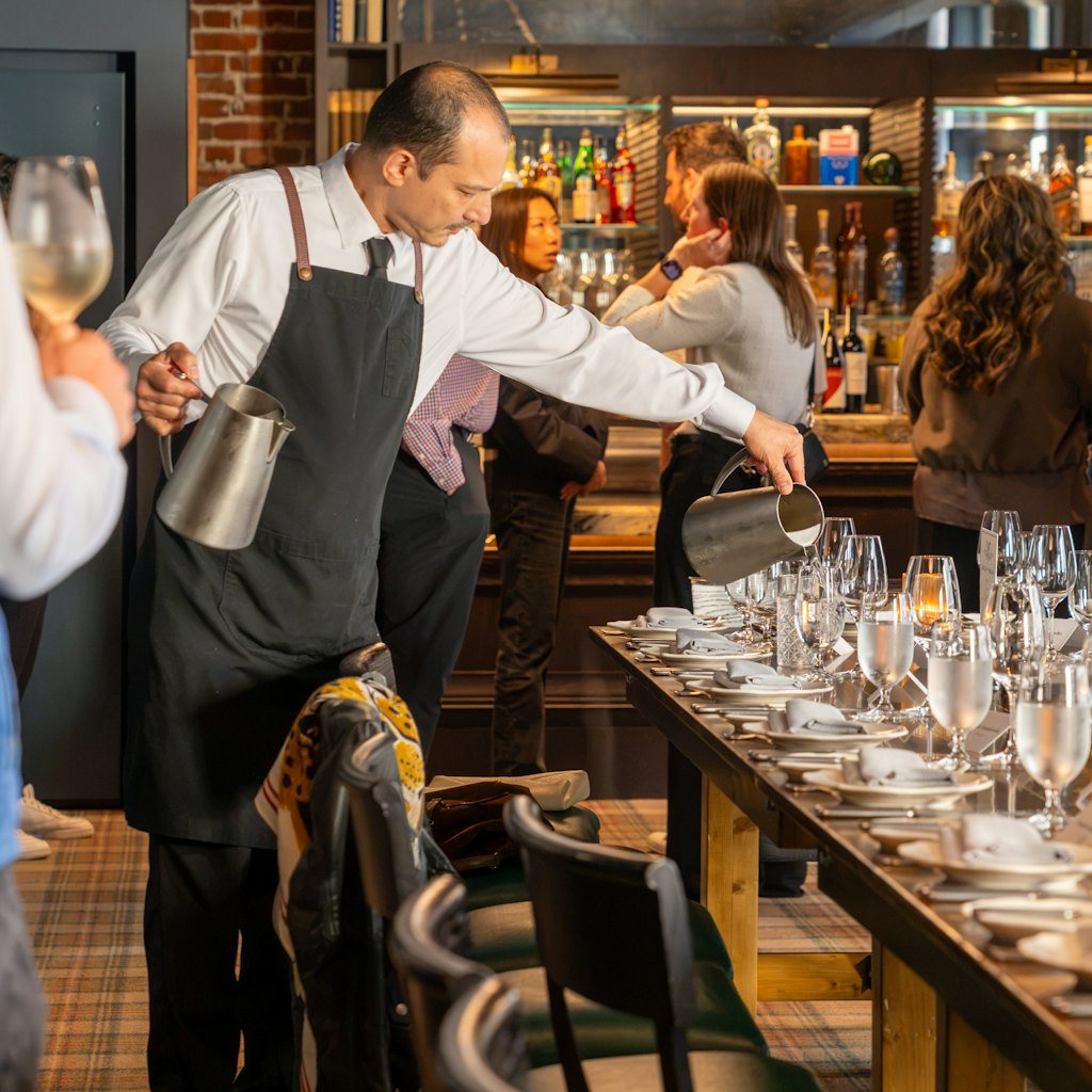 Photo of a waiter pouring water at a laid restaurant table